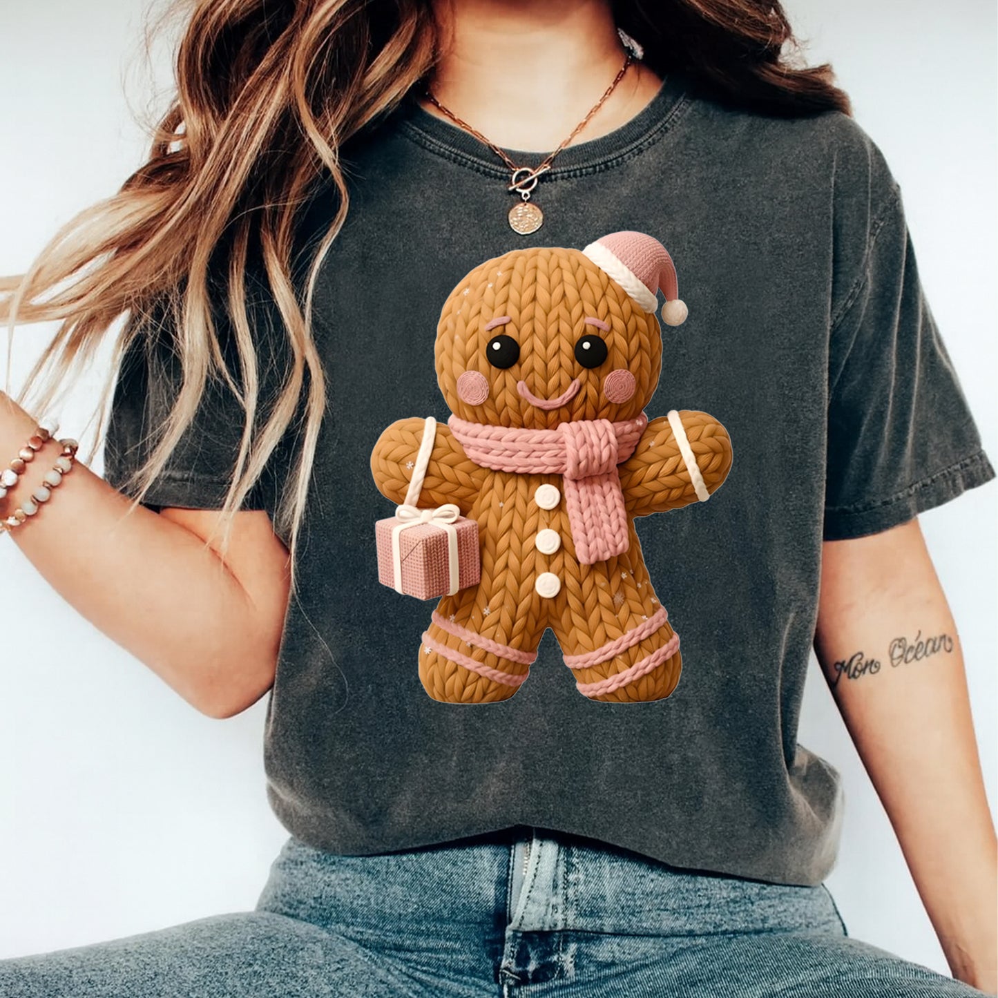 Person wearing a dark gray t-shirt with a knitted gingerbread man design.
