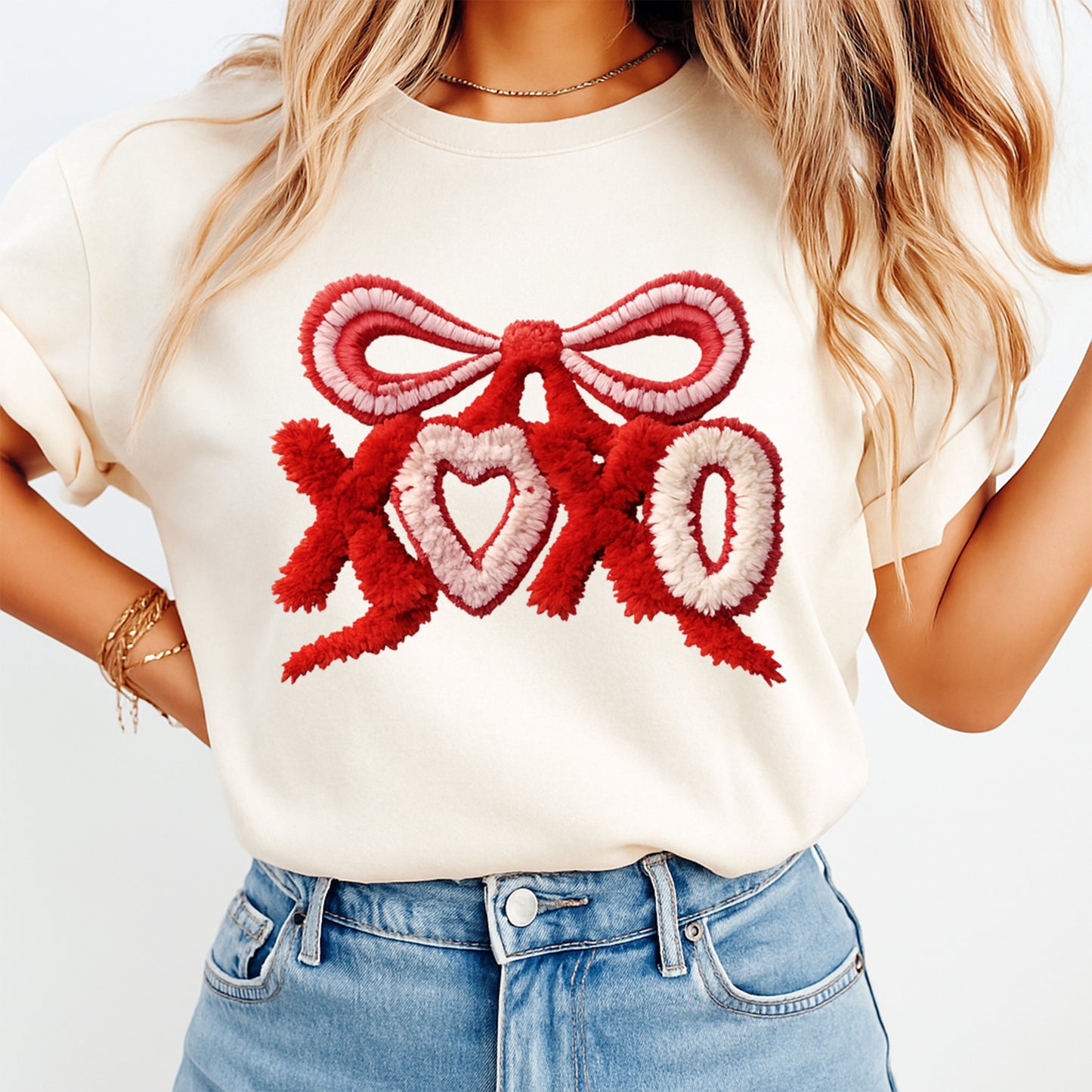Person wearing a white t-shirt with a red and pink bow design and 'XOXO' text.