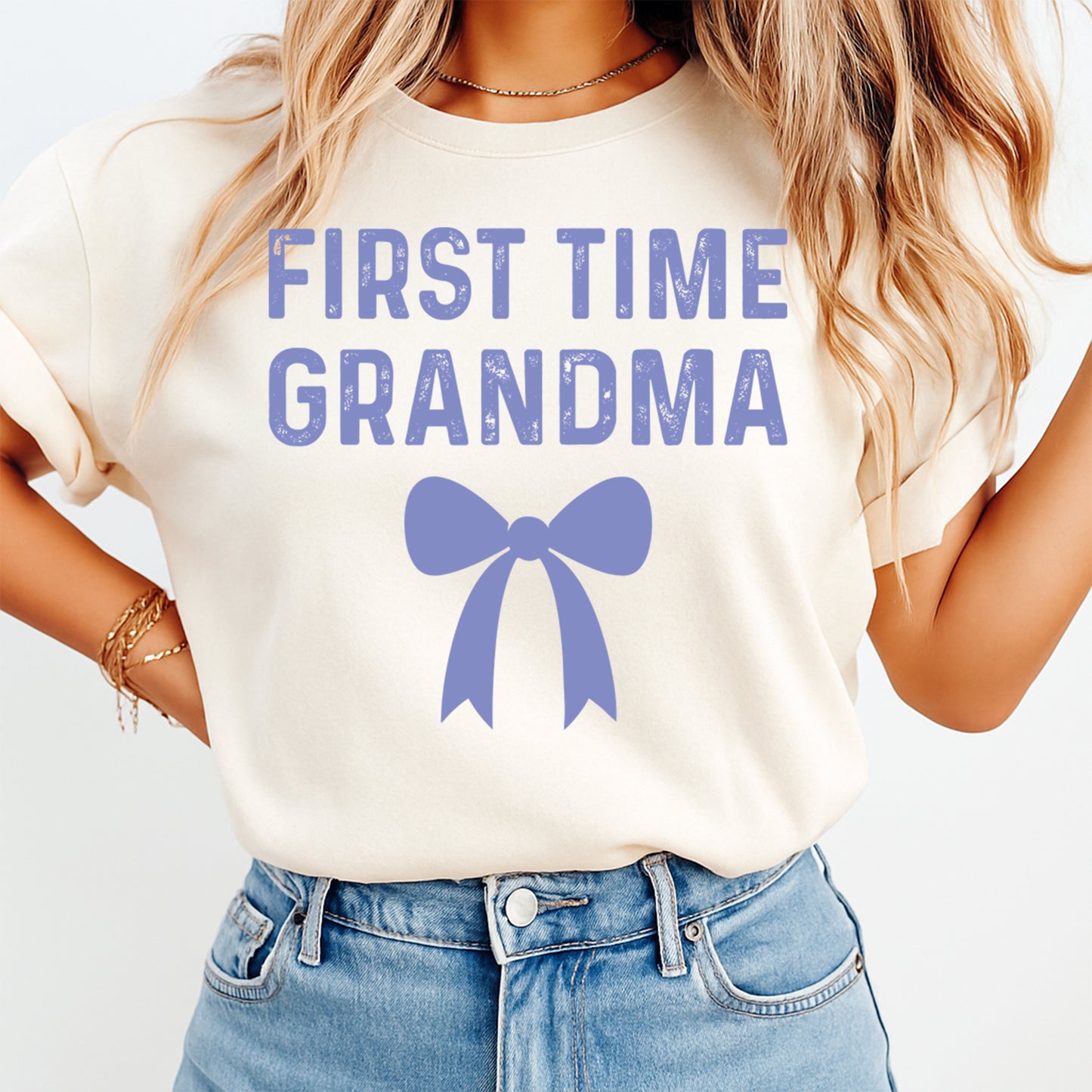 Cream t shirt mockup showing the text First Time Grandma with a blue bow graphic, family announcement graphic tee
