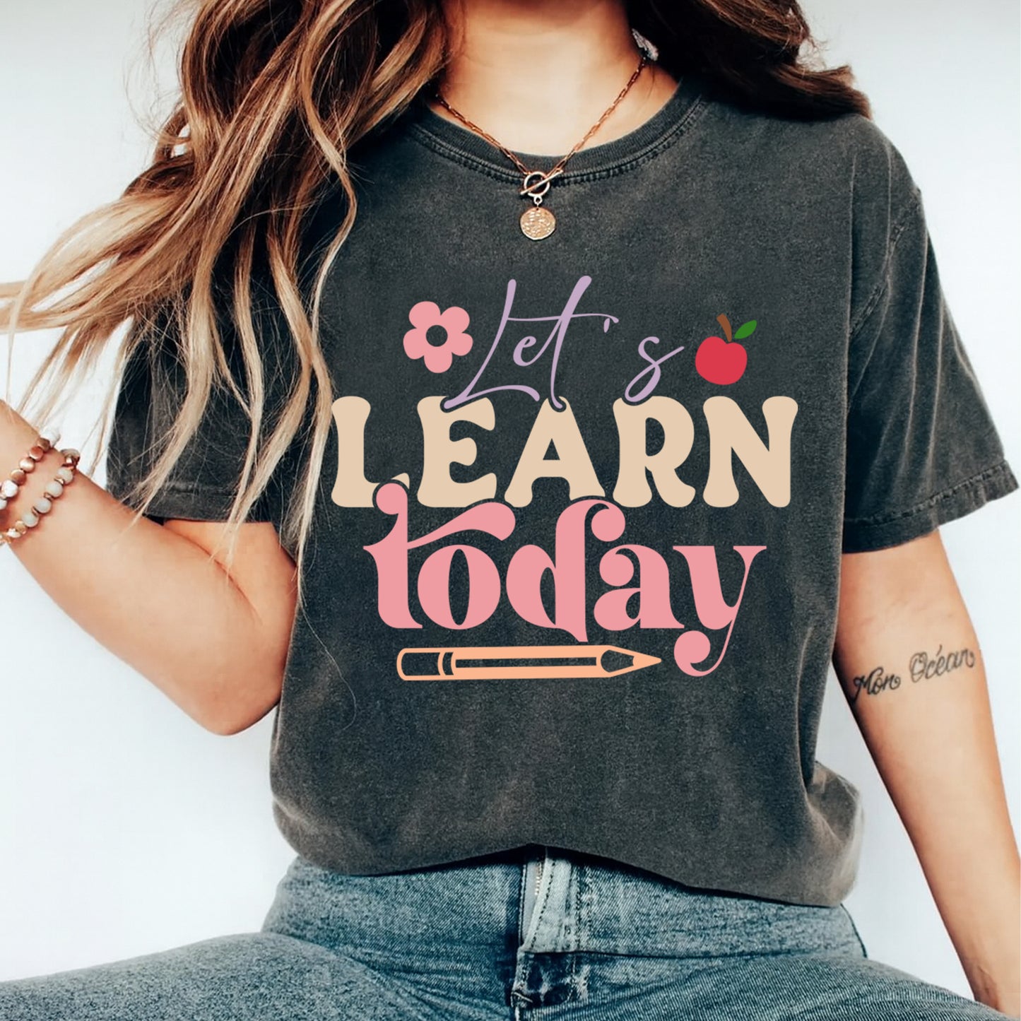 Dark gray t shirt mockup showing the text Lets Learn today with pastel lettering and school themed graphics, teacher graphic tee