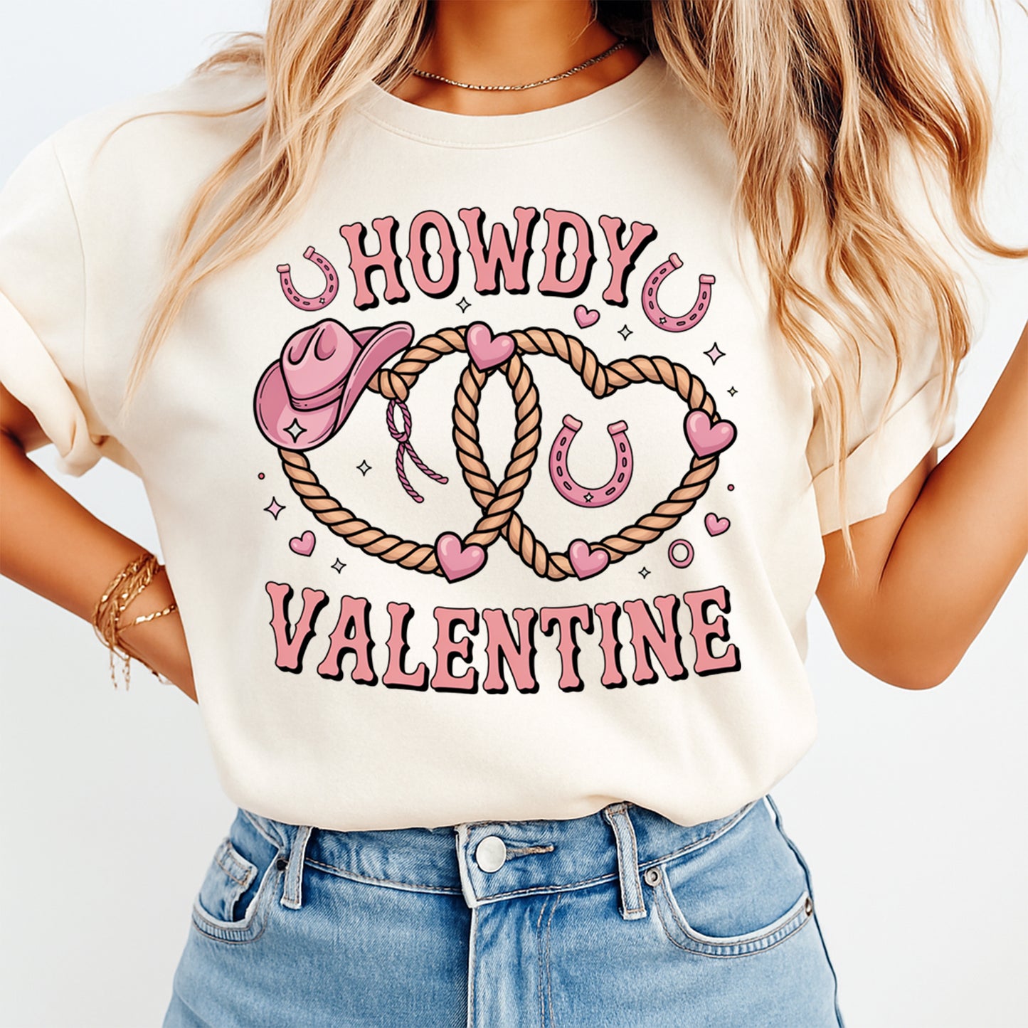 Cream t shirt mockup showing Howdy Valentine western rope heart graphic with pink cowgirl hat and horseshoe details on the front