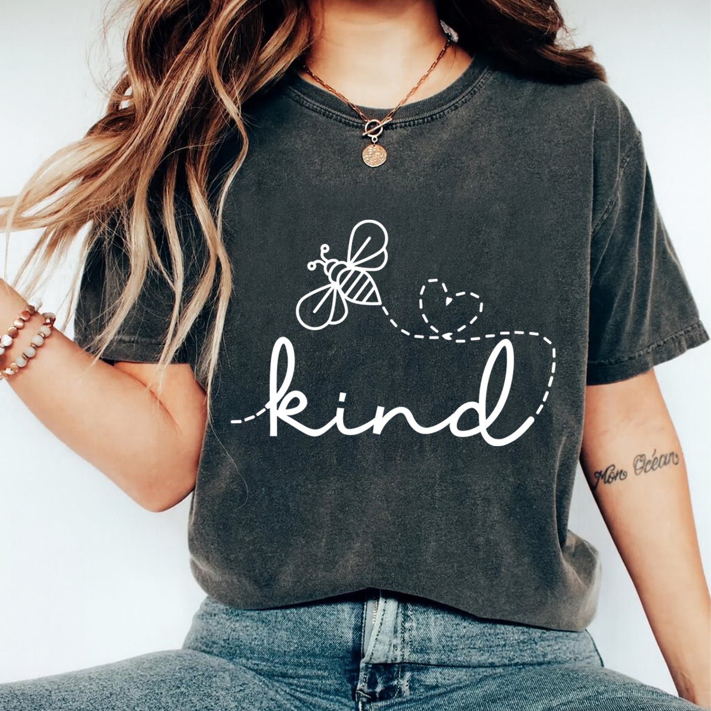 dark shirt mockup showing white kind script with bee and heart flight path graphic