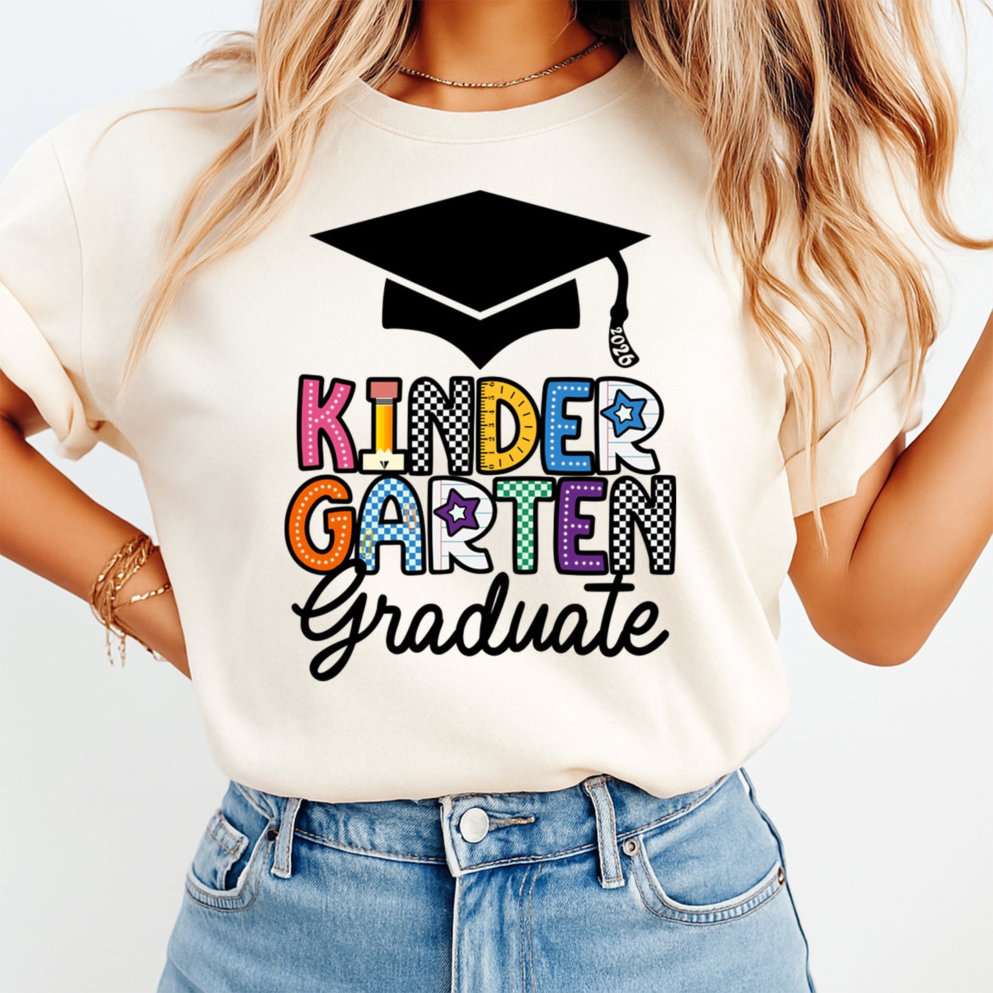 Cream shirt mockup featuring a Kinder Garten Graduate 2026 ready to press dtf transfer with graduation cap and colorful school lettering.