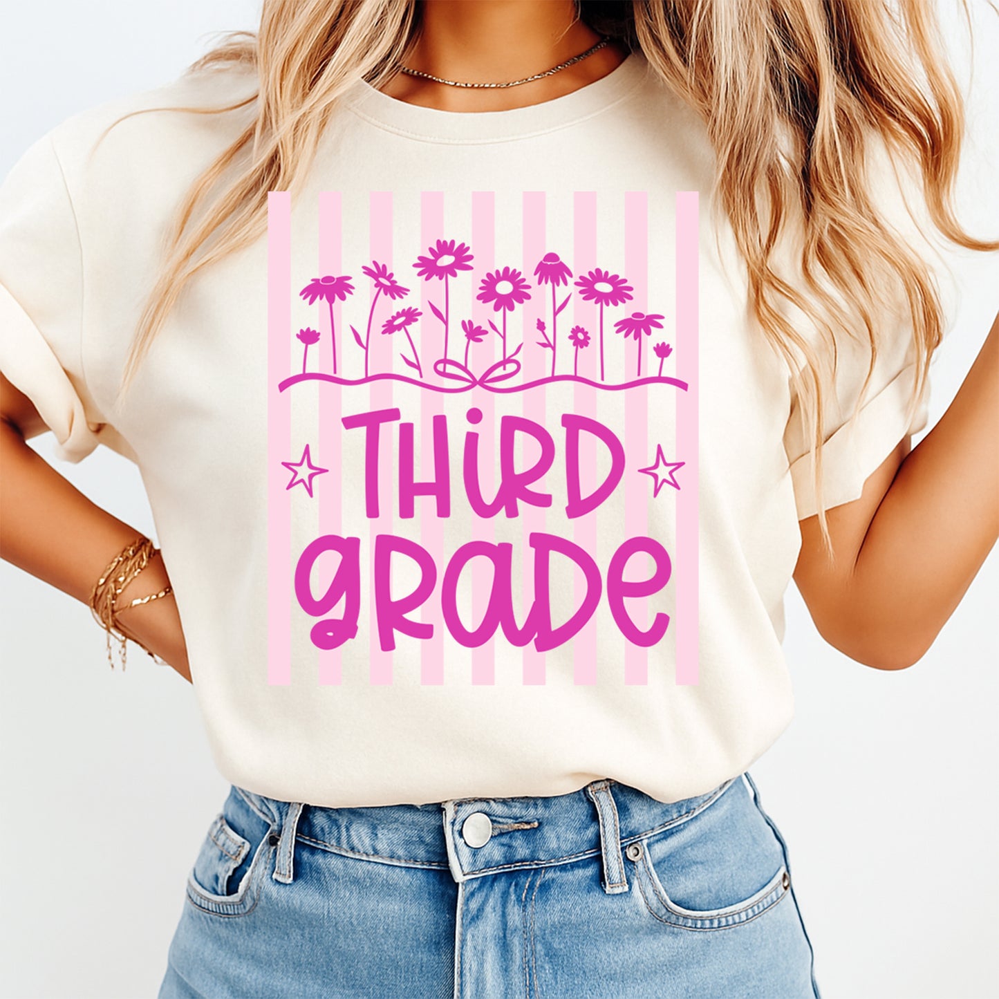Person wearing a white t-shirt with 'Third Grade' in pink text and floral designs on a light background