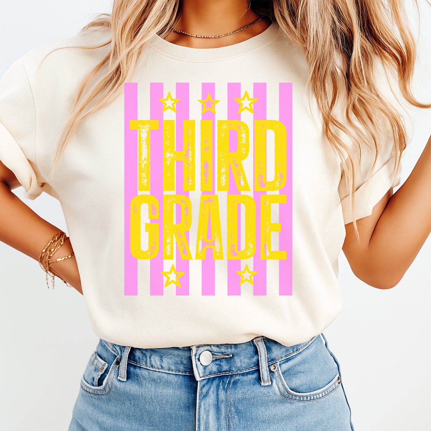 Person wearing a white t-shirt with 'THIRD GRADE' in yellow and pink stripes.