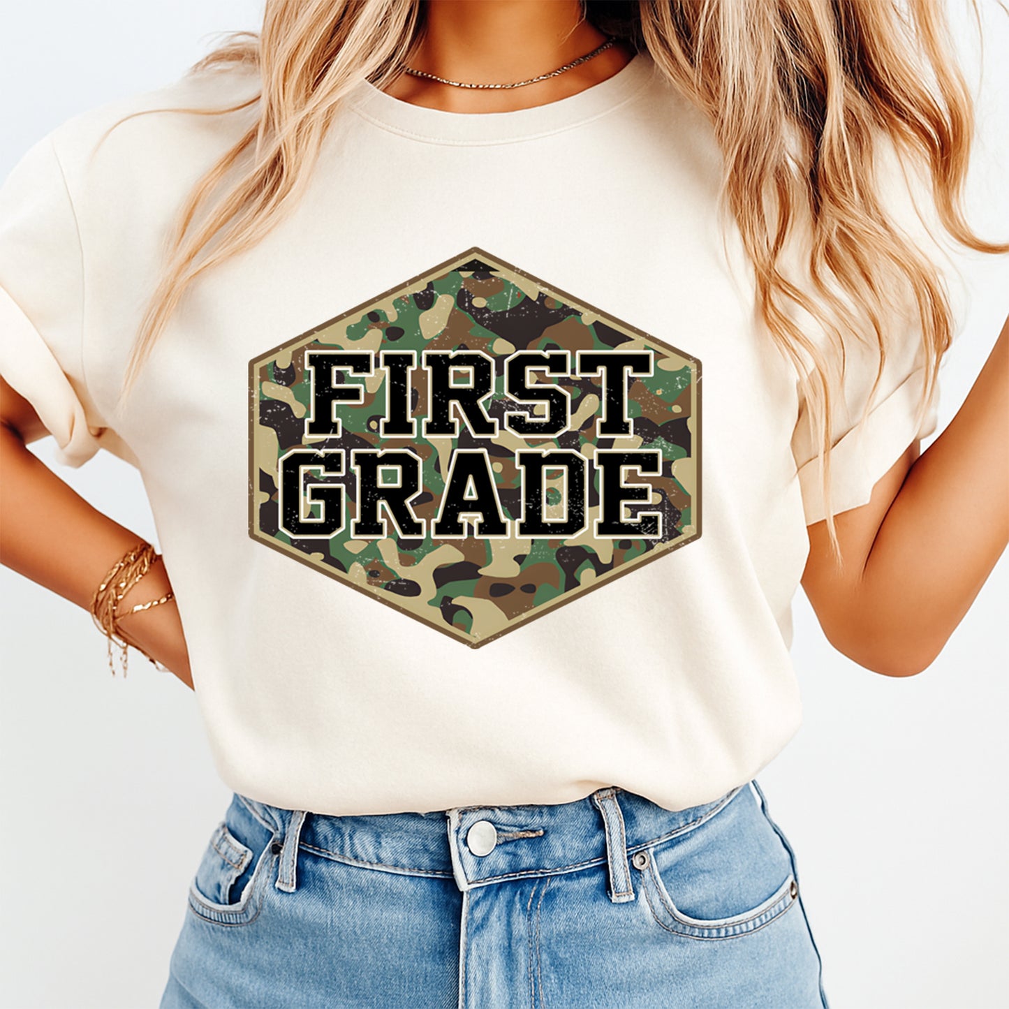 Person wearing a white t-shirt with 'FIRST GRADE' in camouflage hexagon design.