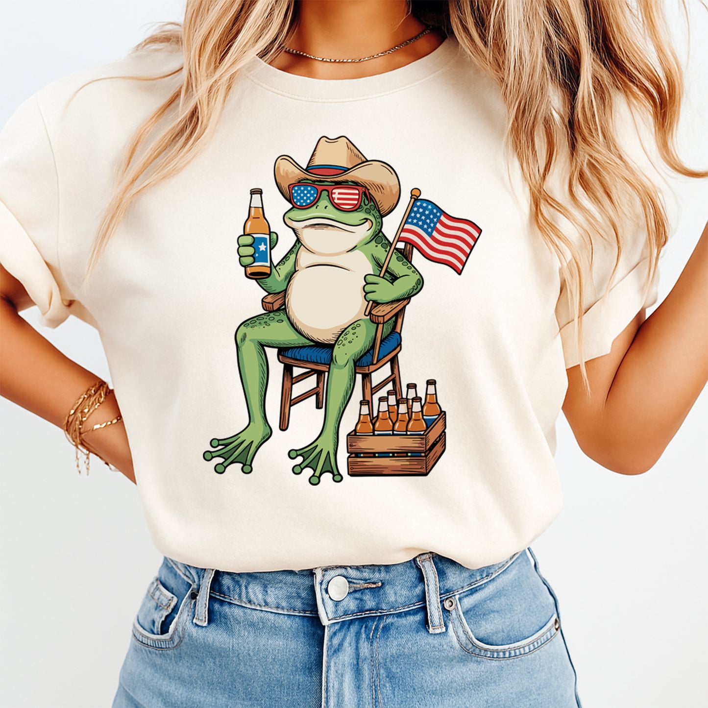 Person wearing a t-shirt with a frog graphic holding an American flag and beer bottle.