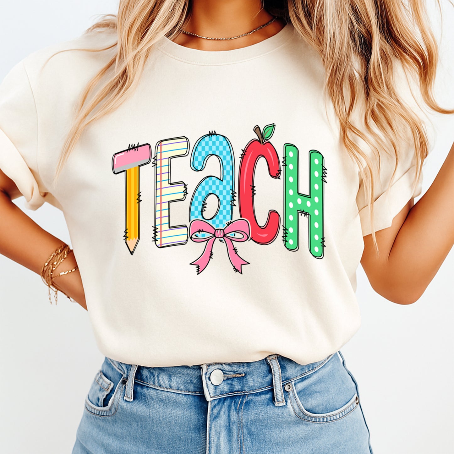 Person wearing a white t-shirt with colorful 'TEACH' text and an apple graphic.