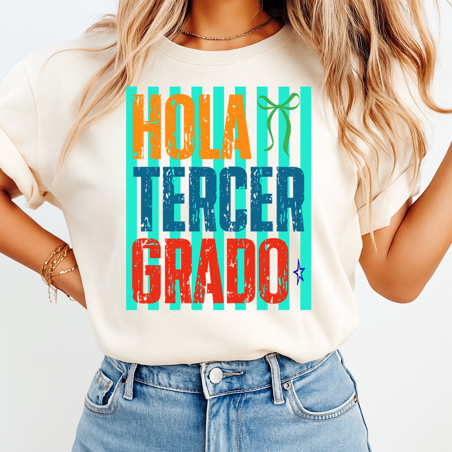 Person wearing a t-shirt with 'Hola Tercer Grado' text in colorful letters on a plain background