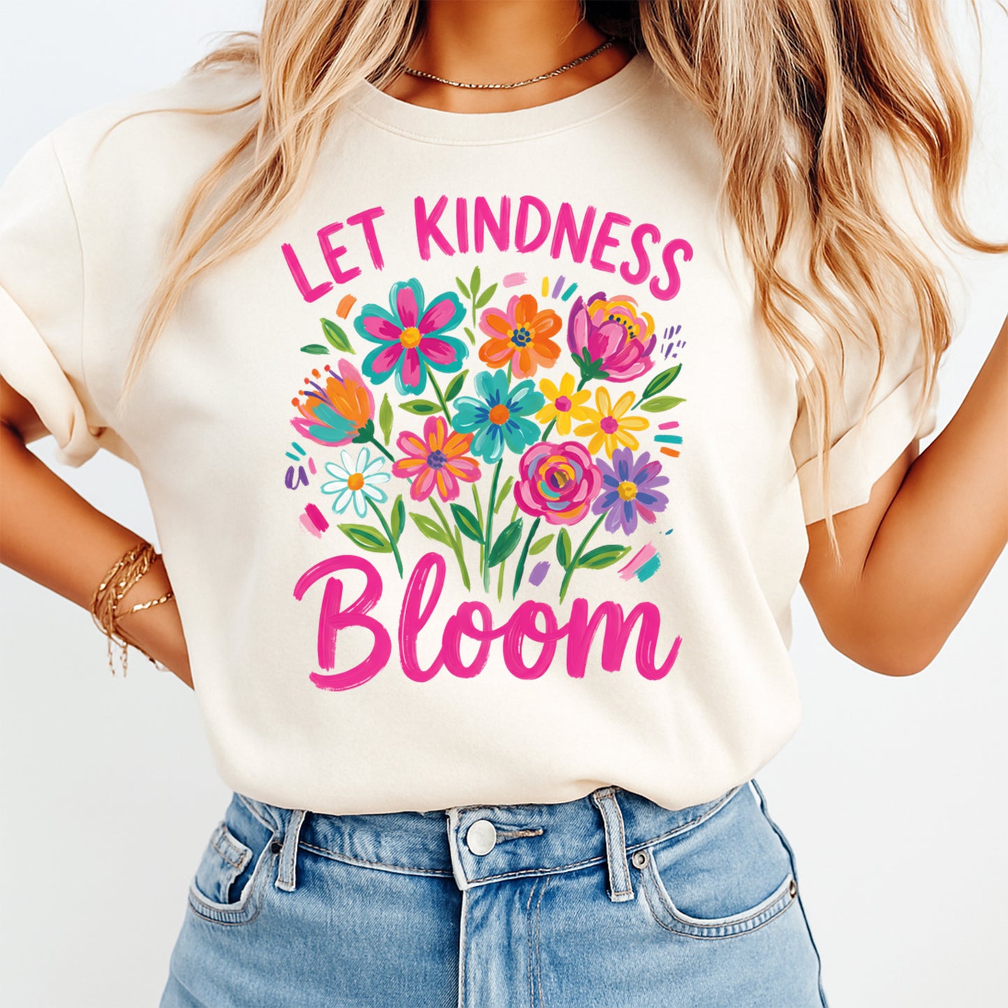 Person wearing a white t-shirt with colorful floral design and 'Let Kindness Bloom' text.