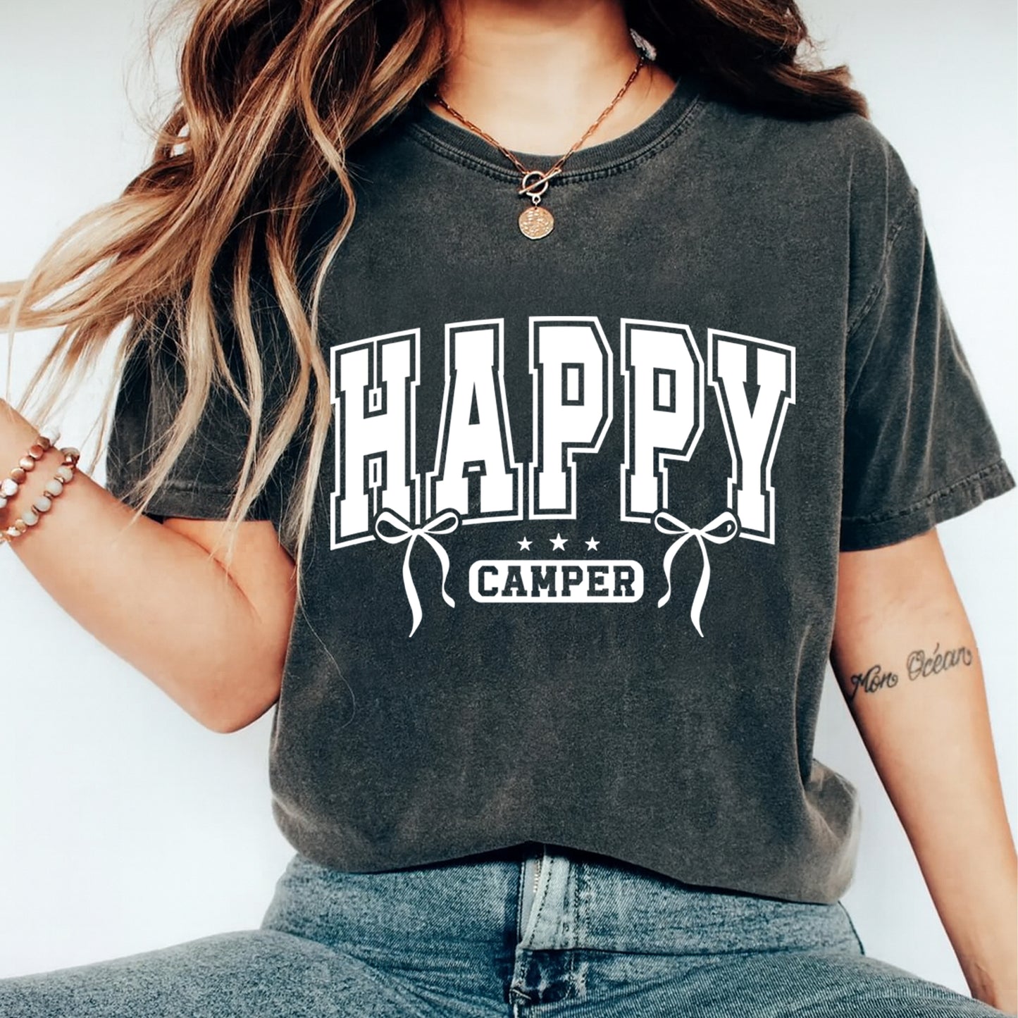 Person wearing a dark gray t-shirt with 'Happy Camper' text on a white background
