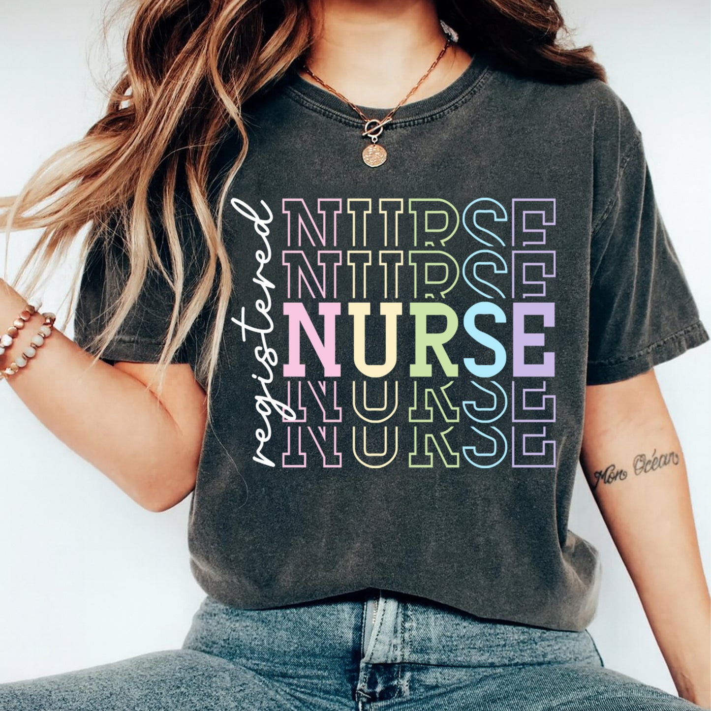 Person wearing a dark gray t-shirt with 'NURSE' in colorful letters and 'registered nurse' text.