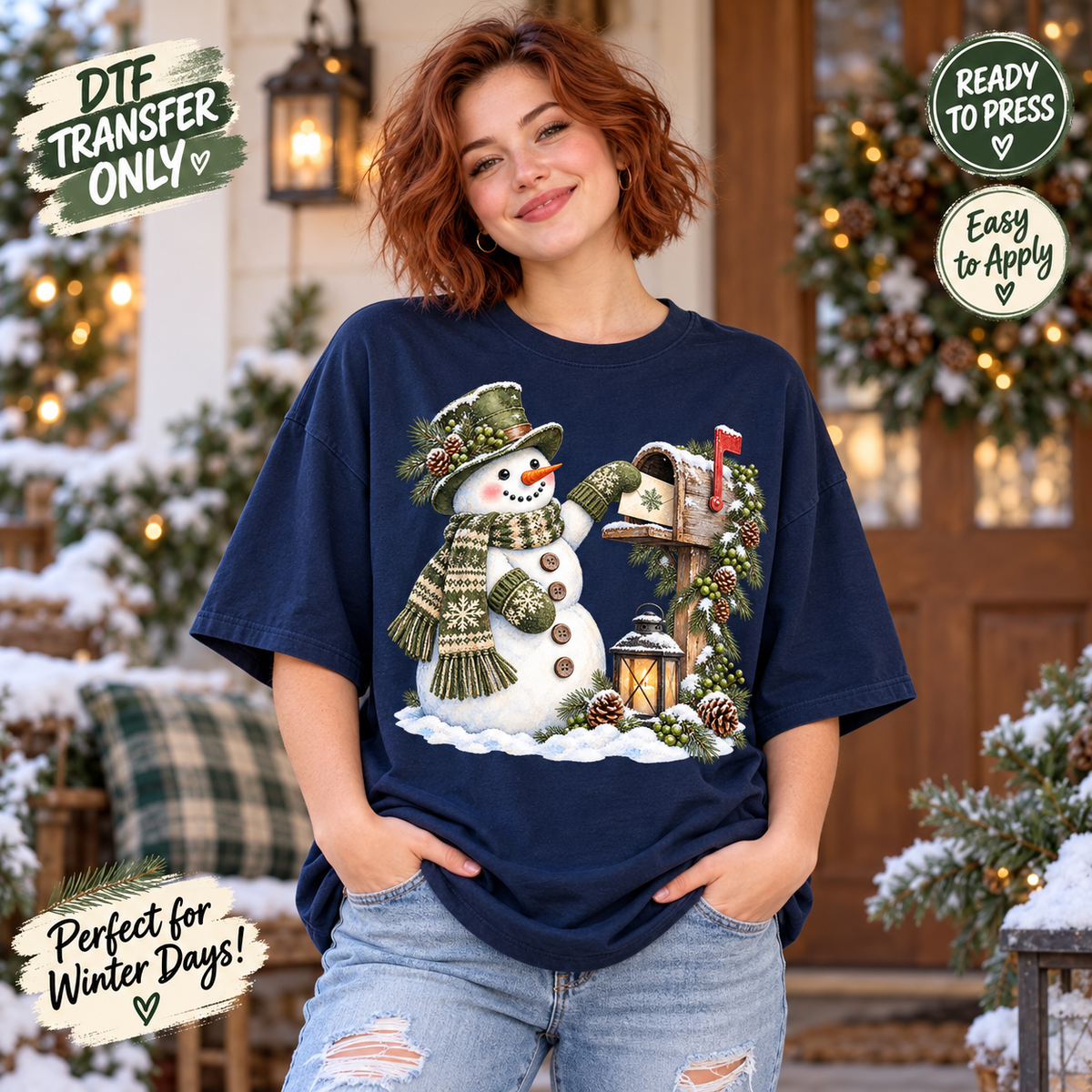 A woman wearing a navy blue t-shirt with a festive Christmas snowman and mailbox graphic, posed in front of a decorated holiday porch. The image includes promotional badges for DTI transfer and customization.