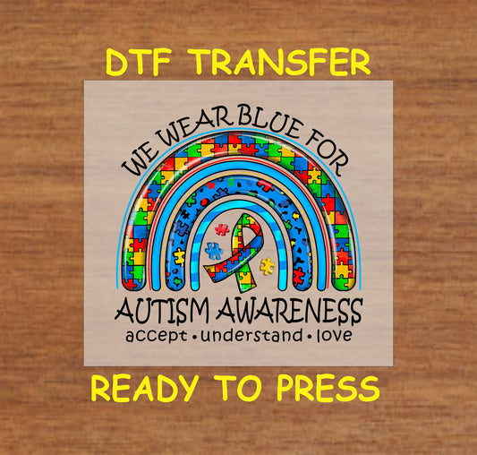 Vibrant "We Wear Blue for Autism Awareness" DTF transfer with a puzzle-piece rainbow and ribbon design.