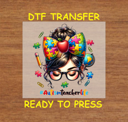 DTF transfer design with a teacher's bun, a puzzle-piece bow, and school supplies, featuring the hashtag #AutismTeacherLife.