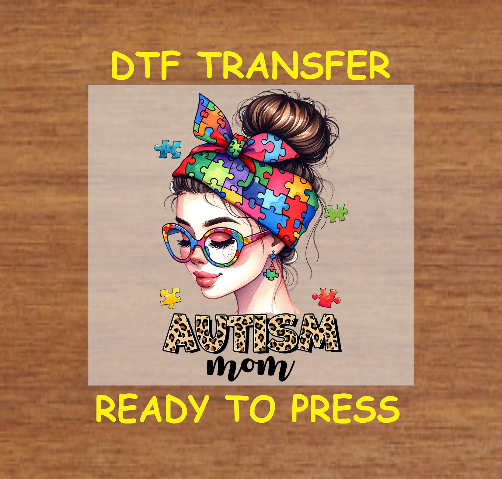 "DTF transfer featuring a colorful puzzle piece bow and glasses with the phrase 'AUTISM Mom' in a bold leopard print font."