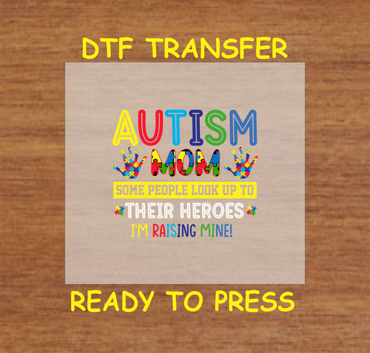"DTF transfer featuring the phrase 'AUTISM MOM' with colorful puzzle pieces, handprints, and the message 'Some people look up to their heroes, I'm raising mine!'"