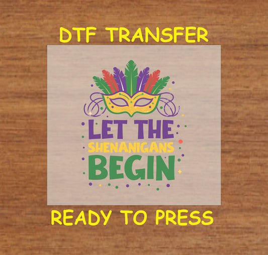 DTF transfer with "Let the Shenanigans Begin" text, masquerade mask, feathers, and bead accents.