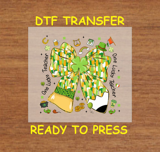 One Lucky Teacher St. Patrick’s Day DTF transfer with a large green and gold bow, clovers, and school-themed accents.