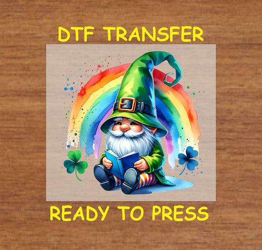 Gnome in green hat reading under a watercolor rainbow with shamrocks.