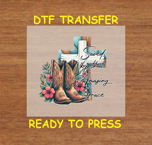 Christian DTF transfer with a wooden cross, cowboy boots, flowers, and "Saved by That Amazing Grace" text.