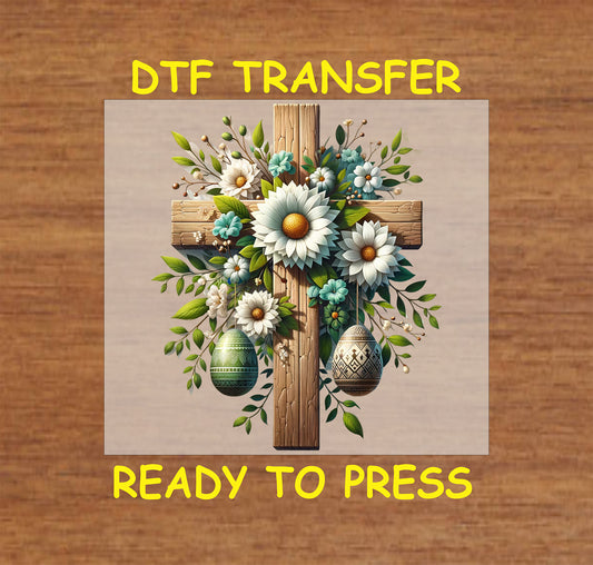 Wooden cross with white flowers, greenery, and decorative Easter eggs in a Christian DTF transfer.