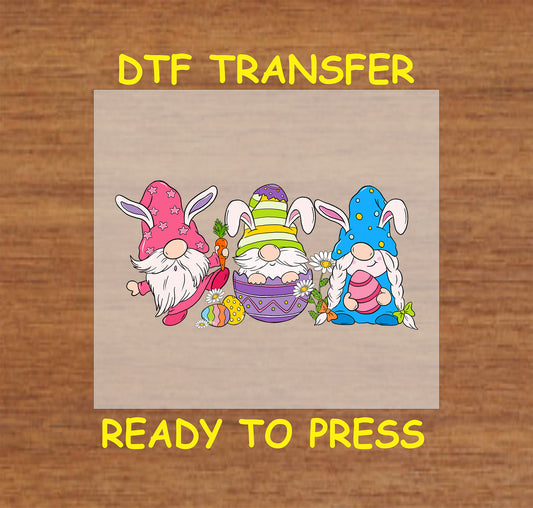 DTF transfer of three Easter gnomes with bunny ears, holding eggs, surrounded by flowers and carrots.
