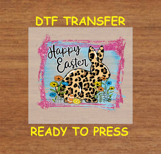 DTF transfer featuring a leopard-print bunny, colorful spring flowers, Easter eggs, and "Happy Easter" text on a rustic painted background.