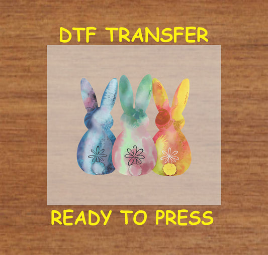 Three watercolor-style bunnies in pastel colors with floral details, Easter DTF transfer.