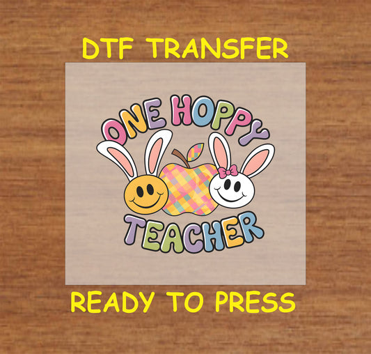 One Hoppy Teacher Easter DTF transfer with bunny-eared smiley faces, plaid apple, and colorful text.