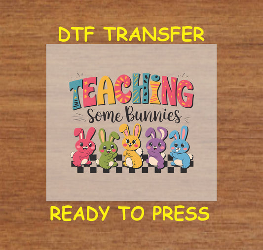 Teaching Some Bunnies DTF transfer with colorful bunnies sitting on a pencil and bold Easter-themed text.