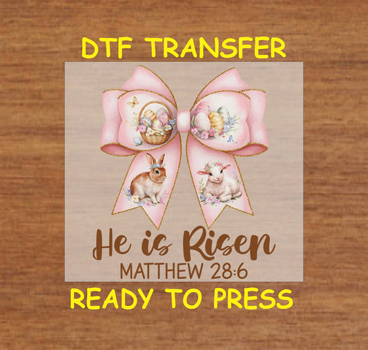 Pink bow with Easter eggs, bunny, lamb, and "He Is Risen – Matthew 28:6" text DTF transfer.