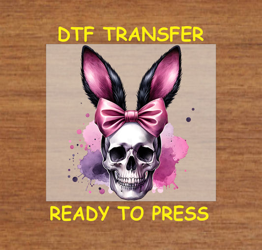 Skull with pink bunny ears, bow, and watercolor splatter.