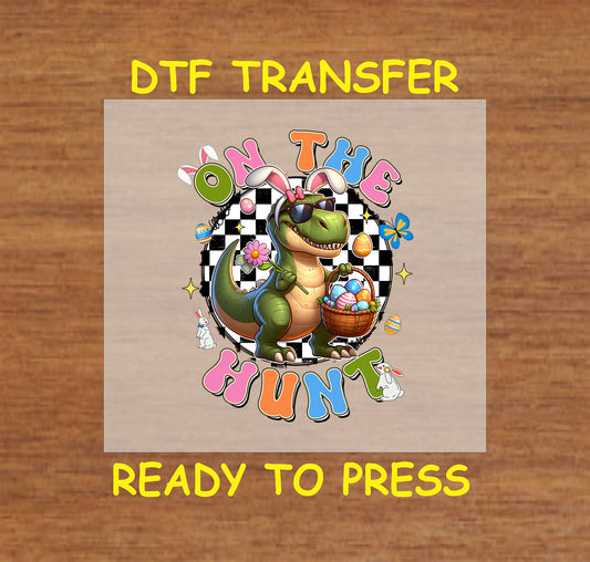 On The Hunt DTF transfer with a dinosaur in bunny ears, sunglasses, and an Easter basket on a checkered background.