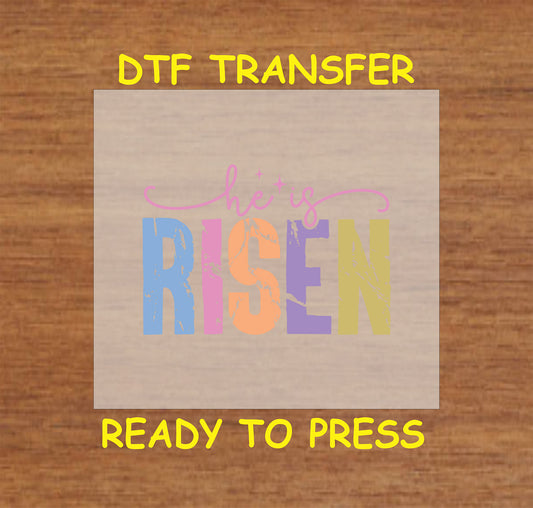 He Is Risen DTF transfer with pastel distressed lettering in a modern script.