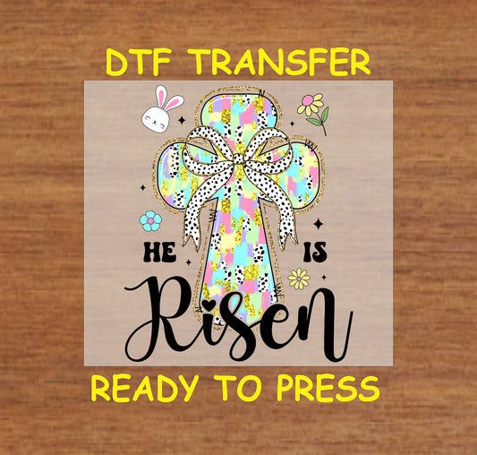 Easter DTF transfer with a colorful cross, polka dot bow, and "He Is Risen" text.