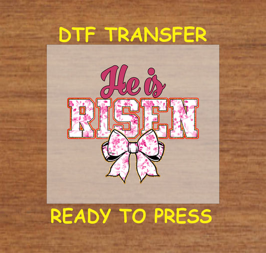 "He Is Risen" text with floral print and bow detail.