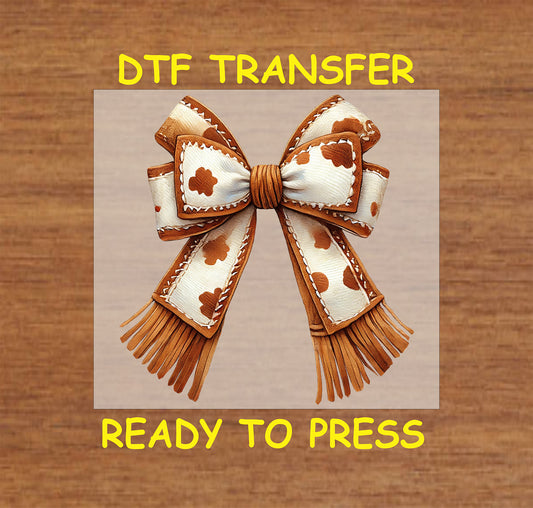 Cow print bow with stitched leather details and fringe accents.