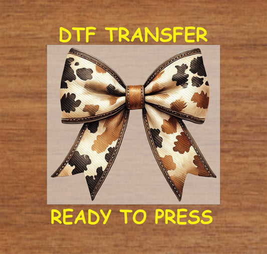 Cow print bow with leather-textured accents and stitched details.