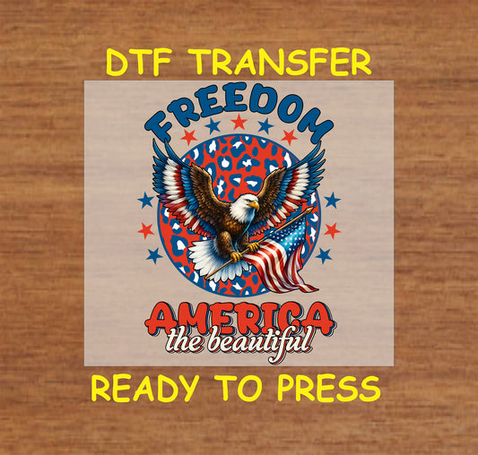 Eagle holding American flag over leopard background with Freedom America the Beautiful text.