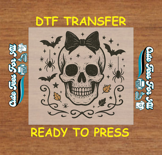 Grinning skull with bow surrounded by bats, spiders, leaves, and stars on Halloween DTF transfer

