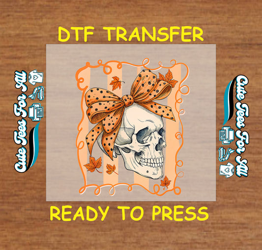 Skull with orange polka dot bow surrounded by autumn leaves and orange swirl frame

