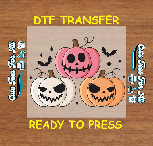 Pink, white, and orange jack-o'-lanterns with spooky faces surrounded by bats and sparkles on Halloween DTF transfer

