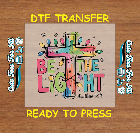 Christian Christmas DTF transfer with colorful cross, lights, and Be the Light Matthew 5:14 text.