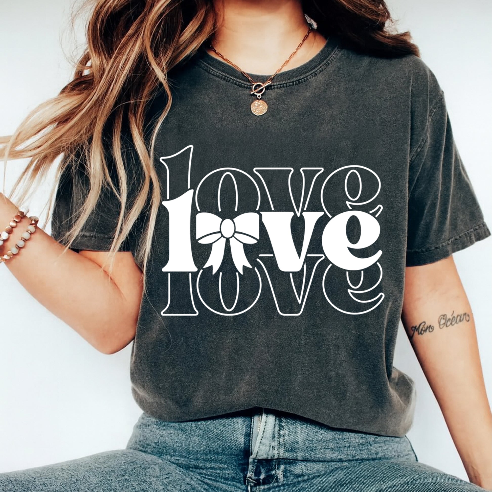 Person wearing a dark gray t-shirt with 'LOVE' text and a bow graphic.