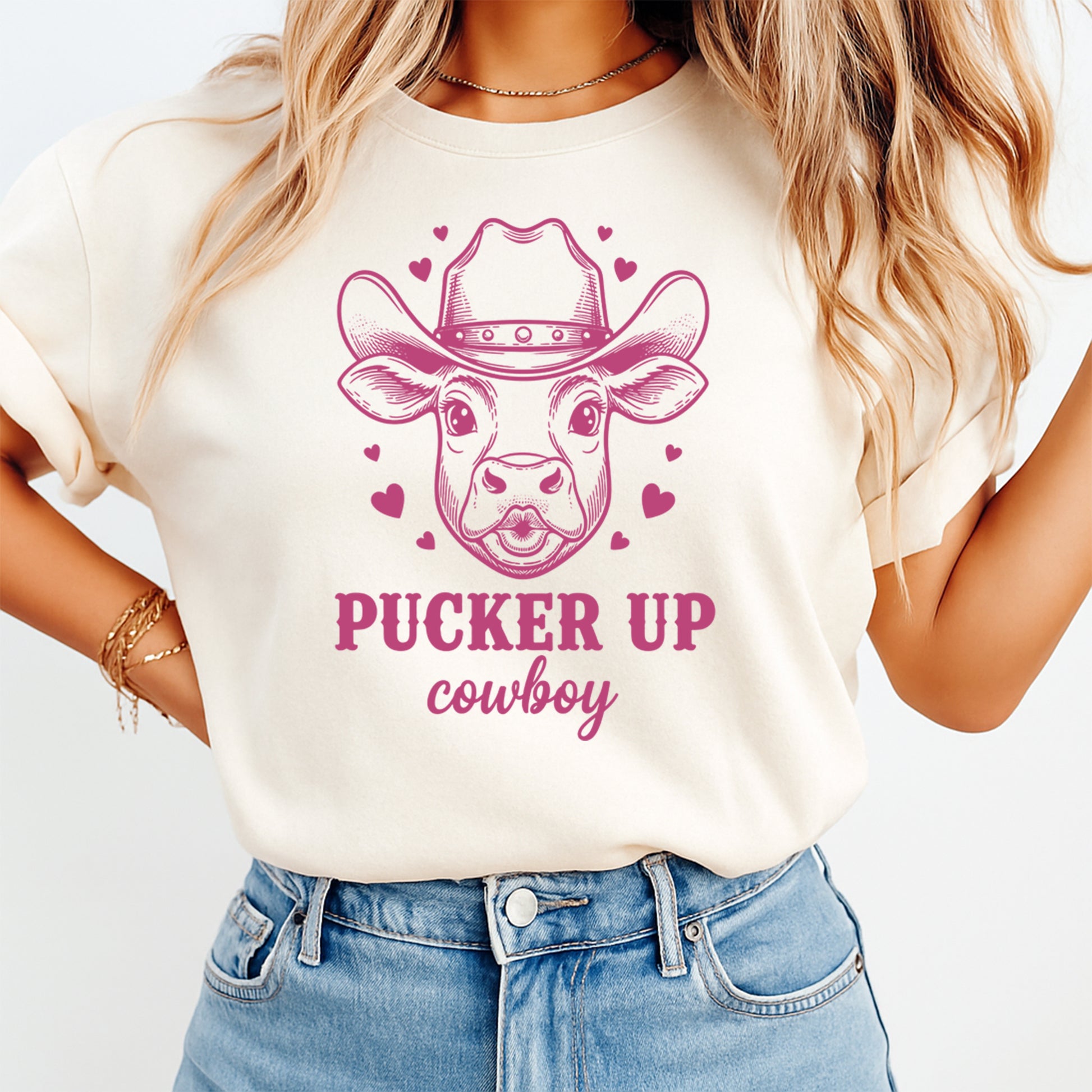 Person wearing a white t-shirt with a pink cow graphic and text on a plain background