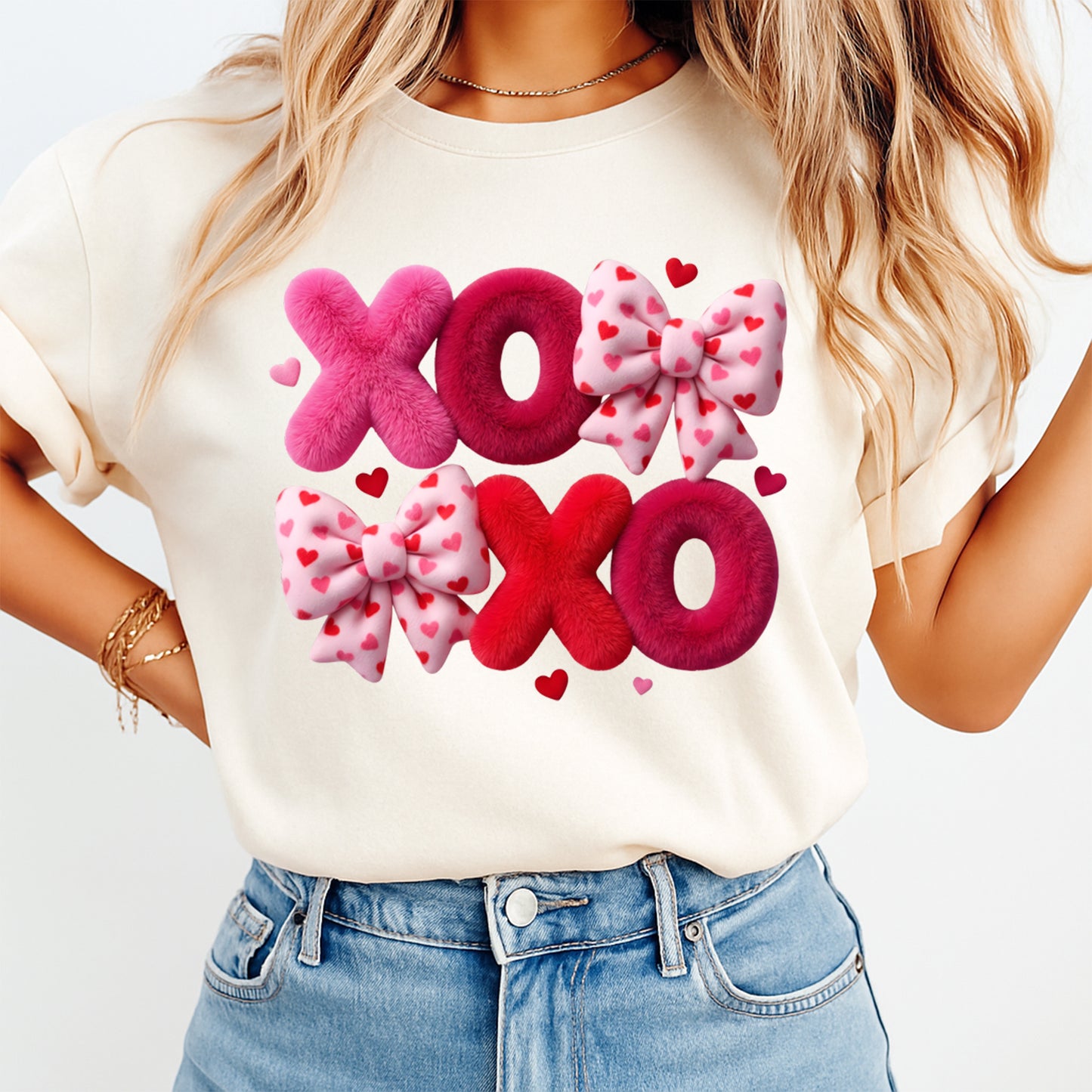 Person wearing a white t-shirt with pink and red 'XO' design and bows.