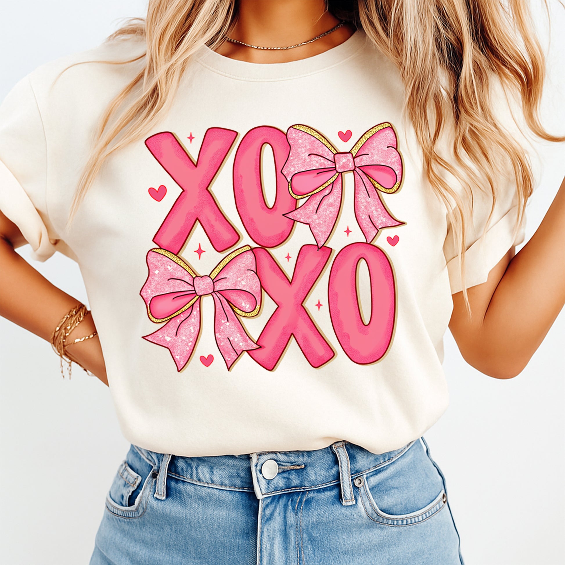 Cream t shirt mockup showing Valentine’s Day XOXO pink letter graphic with glitter bows and heart accents on the front