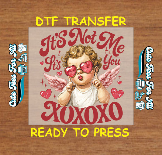 Ready to press dtf Valentine transfer with “It’s Not Me It’s You XOXOXO” text, cupid illustration, heart sunglasses, wings, and red heart accents