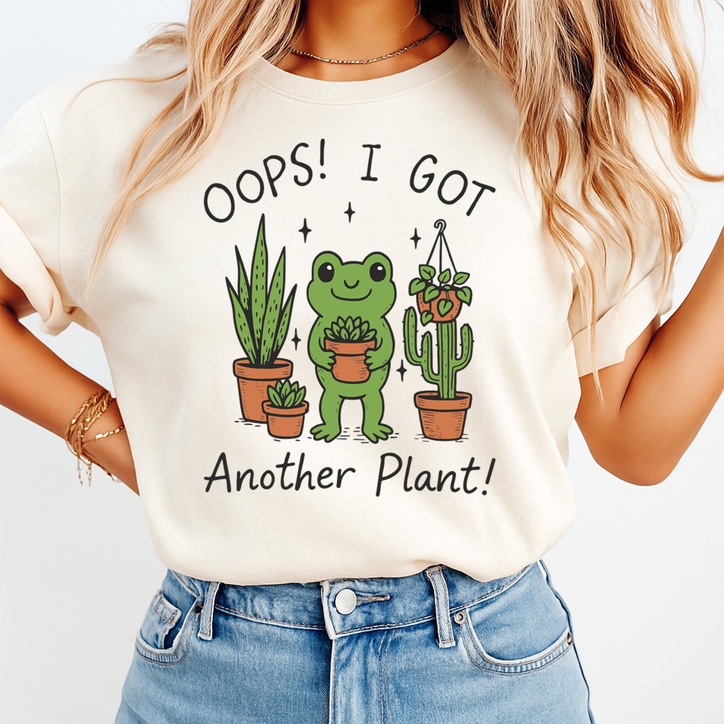 Plant lover shirt mockup showing frog illustration with Oops I Got Another Plant phrase on light colored tee